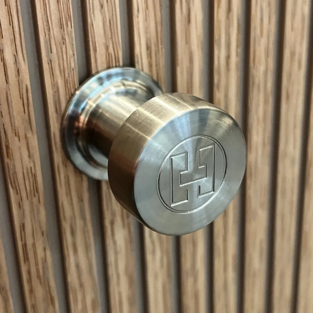 Hassel&Teudt HKN01L - Møbelgreb med H&T logo, PVD Børstet Stål